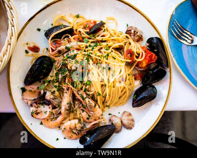 Vista dall'alto di spaghetti allo scoglio o spaghetti con frutti di mare servita in un piatto bianco con gamberetti e altre conchiglie di mare Foto Stock
