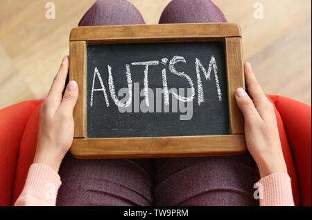 Donna che mantiene lavagna con la parola 'l'Autismo' sulle ginocchia, primo piano Foto Stock