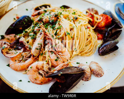Spaghetti allo scoglio o spaghetti con frutti di mare servita in un piatto bianco con gamberetti e altre conchiglie Foto Stock