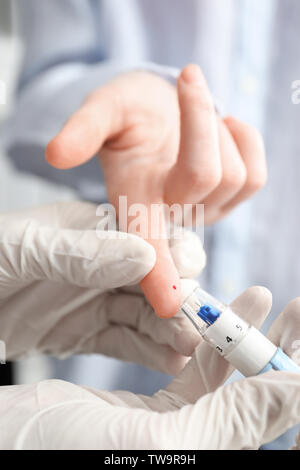 Medico tenendo campione di sangue del paziente con lancetta penna, closeup. Il controllo del diabete Foto Stock