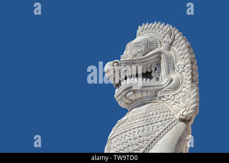 La scultura di antica pietra bianca statua singha isolato sul cielo azzurro sfondo nella parte anteriore del tempio a Bangkok, Thailandia, Sud-est asiatico Foto Stock