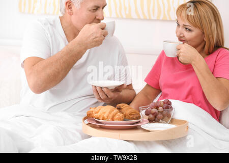 Coppia matura avente la colazione a letto. Mattina romantica Foto Stock