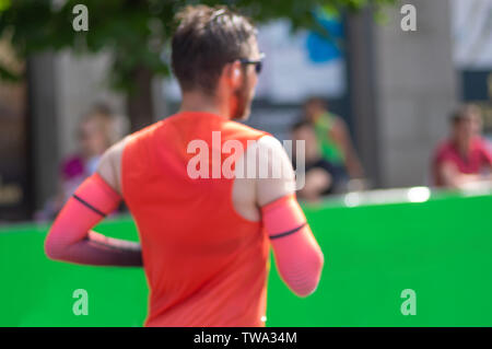 Sfocata sport background - la metà superiore del corpo uomo indossa maglietta rossa e manicotti in esecuzione su una strada Foto Stock