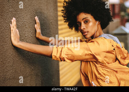Adatta la giovane donna africana che si allena contro un muro. esercizio fisico femminile al mattino all'aperto. Foto Stock