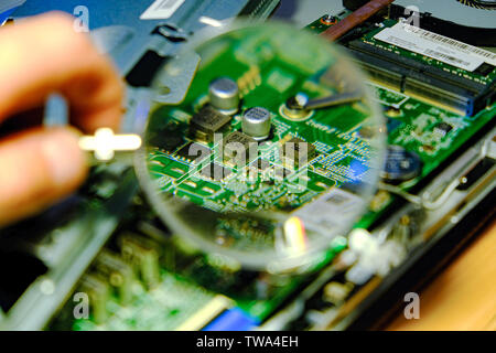 La scheda madre viene ingrandita attraverso una lente di ingrandimento. Gli aggiornamenti hardware del processore del computer del servizio componente della scheda madre. Il concetto Foto Stock