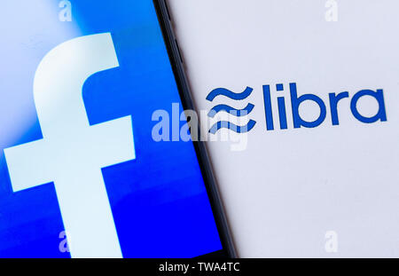 Foto del logo di Facebook sullo schermo dello smartphone e la brochure con il logo di libra. A titolo illustrativo per notizie su Libra cryptocurrency annuncio. Foto Stock