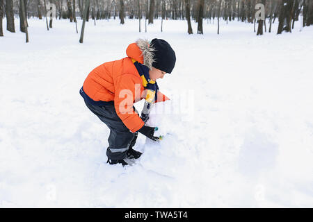Carino boy rendendo pupazzo di neve nel parco sulla vacanza invernale Foto Stock