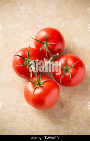 Quattro pomodori maturi sul vitigno importato dai Paesi Bassi e comprato da un supermercato nel Regno Unito. Fotografato su una pietra di luce sullo sfondo. Il Dorset Foto Stock