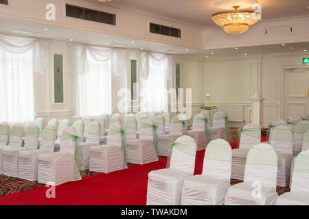 File di sedie vuote con copertine in un luogo del Regno Unito per un ricevimento di matrimonio Foto Stock