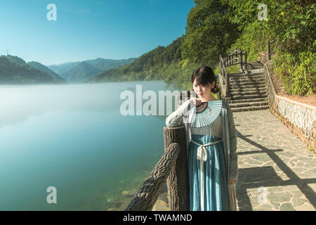 Dongjiang nebbia mattutina 1 (nella prima mattina di estate, vi è nebbia mattutina sul piccolo fiume Dongjiang. Una donna in un costume antico gode di uno splendido scenario sulla superficie del fiume). Foto Stock