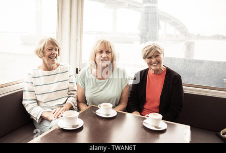 Gioiosa amici anziani avente un tè o un caffè insieme. Senior amiche in chat di ridere e di divertirsi nel coffee shop a rimanere attivi in pensione Foto Stock