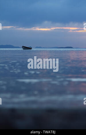 Tramonto sul mare con una barca. Una foto di una piccola barca con un bel tramonto sullo sfondo. Foto Stock