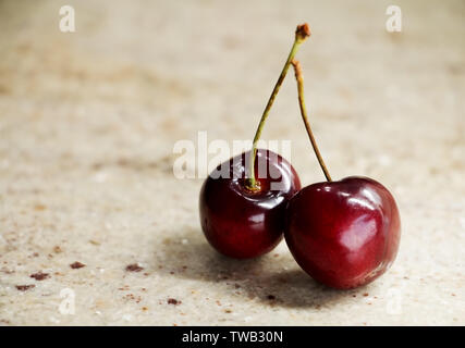 Chiusura del grappolo maturi dolci fresche Ciliege su un tavolo di granito. Spazio per lo sfondo del testo. Banco di pietra vassoio. Profondità di campo. Foto Stock