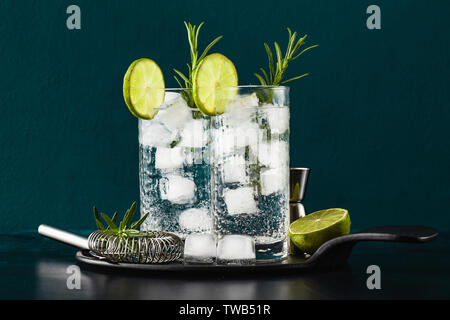 Classic gin tonic cocktail con rametti di rosmarino in bicchieri alti su un tavolo con accessori bar Foto Stock