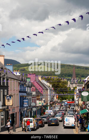 Strada trafficata piccola cittadina irlandese Henry Street e la Chiesa della Santa Croce a Kenmare, contea di Kerry, Irlanda Foto Stock