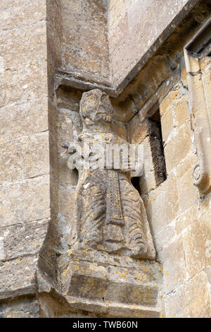 Xii Secolo di pietra la figura di un santo che tiene un libro, la chiesa della Santa Croce, Sherston, Wiltshire, Inghilterra, Regno Unito Foto Stock