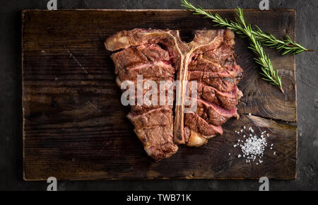 Osteria bistecca alla griglia di tranciato su un pezzo di legno. Scheda di stile rustico, vista dall'alto Foto Stock