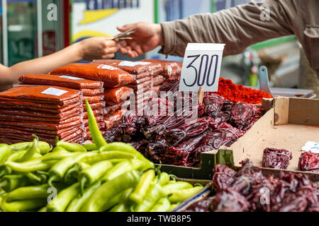 Diversi tipi di verde e peperoni rossi sul marketplace di Belgrado. Sfocare lo sfondo del venditore e le mani del cliente il pagamento in contanti. Foto Stock