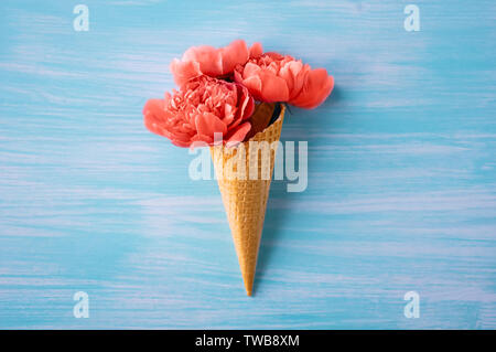 Le Peonie color corallo. Un bouquet di peonie in un cono per gelato. Colore 2019. Il design creativo. minimalismo. Foto Stock