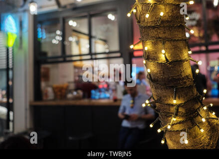 Alla moda di albero decorato con luci nella strada vicino al ristorante esterno zona nel cuore del centro cittadino di Atene Foto Stock