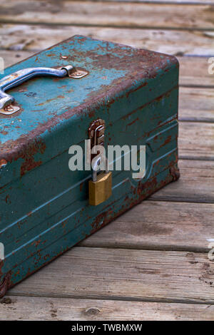 Vecchio arrugginito toolbox bloccato seduto su un legno Foto Stock