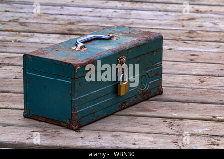 Vecchio arrugginito toolbox bloccato seduto su un legno Foto Stock