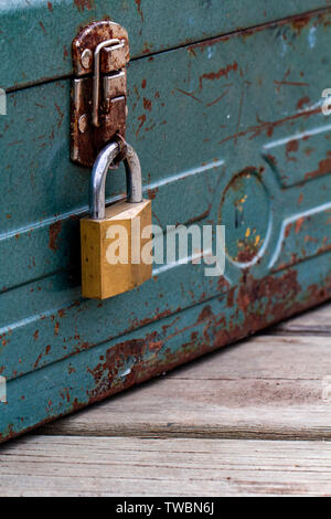 Vecchio arrugginito toolbox bloccato seduto su un legno Foto Stock