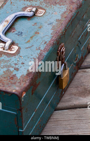 Vecchio arrugginito toolbox bloccato seduto su un legno Foto Stock