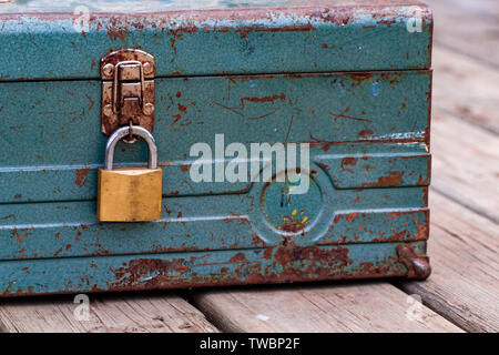 Vecchio arrugginito toolbox bloccato seduto su un legno Foto Stock