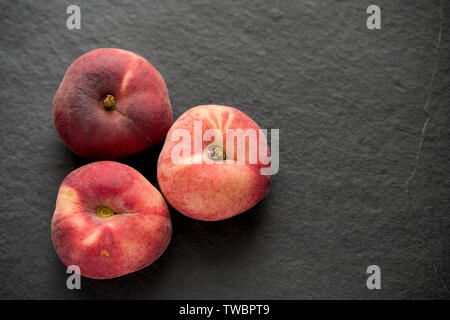 Appartamento pesche importate dalla Spagna e comprato da un supermercato nel Regno Unito. Fotografato al buio su un sfondo di ardesia. Inghilterra REGNO UNITO GB Foto Stock