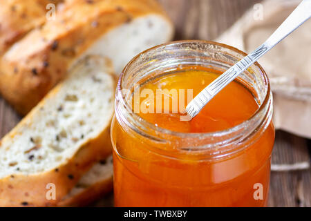 Vaso con marmellata di albicocche sul tavolo di legno Foto Stock