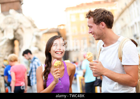 Gelato - giovane mangiare il gelato a Roma in Piazza Navona. Paio mangiare il gelato su vacanze viaggi in Italia, l'Europa. Sorridendo felice coppia giovane in amore divertimento mangiare cibo italiano all'esterno. Foto Stock