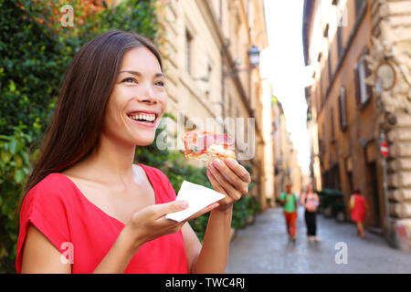 Donna Pizza pizza slice in Italia a Roma sorride felice all'aperto durante i viaggi vacanza ferie. Bellissima gara di misto asiatico donna caucasica godendo il cibo italiano. Foto Stock