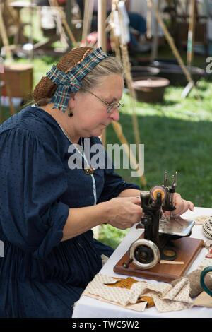 Una donna nel periodo dress dimostra una antica macchina da cucire mentre partecipate a Johnny Appleseed Festival in Fort Wayne, Indiana, Stati Uniti d'America. Foto Stock