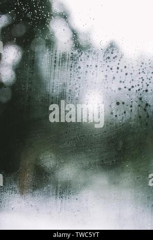 Condensa e pioggia fresca contro un finestrino di un'auto Foto Stock