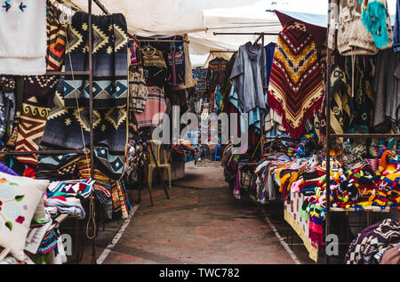 Affollate bancarelle alle popolazioni indigene di tessuto intessuto e negozio di souvenir in Otavalo, Ecuador, uno dei più grandi mercati artigianali in Sud America Foto Stock