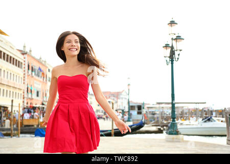 Donna felice in esecuzione in abiti estivi, Venezia, Italia. Ragazza sorridente ridere gioioso divertimento da acqua a Venezia. Bella multirazziale caucasico asiatica giovane donna allegra e vivace. Foto Stock