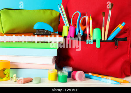 La scuola fornisce su un tavolo di legno contro il colore di sfondo e primo piano Foto Stock