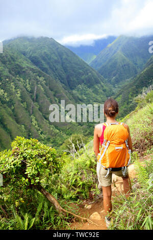 Escursionismo donna alle Hawaii, Waihee ridge trail, Maui, STATI UNITI D'AMERICA. Giovani femmine escursionisti a piedi nella splendida e lussureggiante foresta hawaiano natura paesaggio di montagna. Donna asiatica escursionista indossando uno zaino guardando a vista. Foto Stock