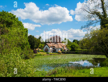 Cottage con il tetto di paglia si riflette nel villaggio piscina a Badger, Shropshire, Inghilterra, Regno Unito Foto Stock