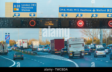 Il traffico pesante su M25 London Orbital in Middlesex, con un30 strada a scivolo e overhead segno indicante la M4, M40 e M1 autostrade nelle vicinanze. Inghilterra, Regno Unito. Foto Stock