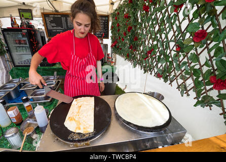 Cuoca facendo una crêpe o pancake su una calda stufa rotonda. Foto Stock