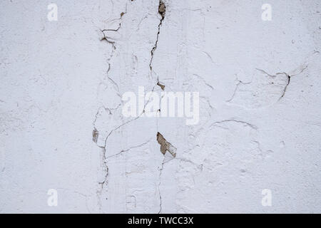 Bianco vecchio muro intonacato con tracce di lunghe crepe Foto Stock