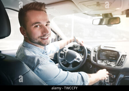 Giovane maschio conducente dietro la ruota. Economia di condivisione o di servizio taxi driver concept Foto Stock