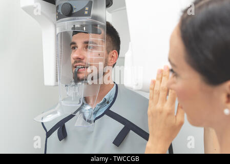 Bel uomo paziente in piedi nella macchina a raggi x. Radiografia panoramica di professional dental clinic. Foto Stock