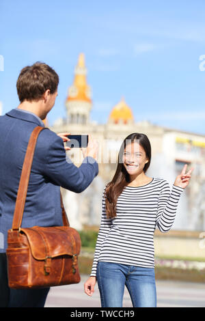 Lo stile di vita di Barcellona di persone. Turista giovane prendendo foto sul viaggio vacanza. Urbano felice coppia giovane prendendo foto con smart phone fotocamera su Plaça de Catalunya Catalonia square, Barcelona, Spagna. Foto Stock