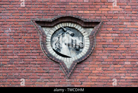 Il bassorilievo di una testa di cavallo su un muro di mattoni. Foto Stock