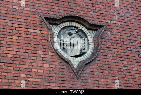 Il bassorilievo di una testa di cavallo su un muro di mattoni. Foto Stock