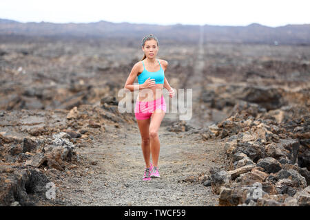 Runner donna triatleta trail running cross country all'esterno in esecuzione sul vulcano. Atleta femminile jogging formazione per correre la maratona al di fuori nel bellissimo paesaggio sulla Big Island, Hawaii, Stati Uniti d'America. Foto Stock