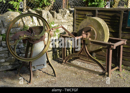 Vecchio ridondante azionato a mano attrezzi agricoli. Una radice di trancia e uno strumento di affilatura delle ruote di pietra arenaria.in una fattoria la penisola Purbeck, Dorset, Foto Stock